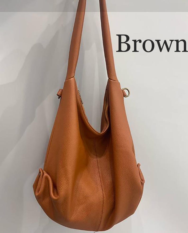 May include: A brown hobo bag with a textured surface, featuring a single long shoulder strap, a central vertical seam, and side pockets with metallic hardware. The word Brown is printed in black text on the upper right side of the image.