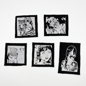 May include: Five black and white patches with manga-style illustrations. The patches feature images of a cat, a zombie-like figure, a person with their brain exposed, a girl with multiple eyes, and a girl with multiple faces.