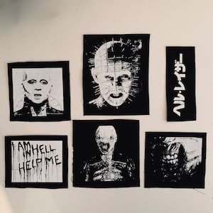 May include: A set of nine black and white iron-on patches featuring horror movie characters and text. The patches include a character with a head full of nails, a character with a long, thin face, a character with a mouth full of teeth, and text that reads "I am hell help me".