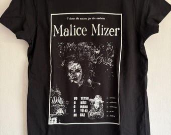 May include: Black t-shirt featuring a white graphic with the text "Malice Mizer" and the phrase "I know the reason for her sadness." The graphic includes illustrations and band member names. The shirt is hanging on a black hanger.