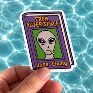 May include: A rectangular sticker featuring a purple book cover with the text FROM OUTER SPACE and Jose Chung in orange. The centre shows a green square with a grey alien illustration holding a cigarette in its mouth, rendered in a cartoon style.