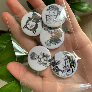 May include: Five round, white, holographic buttons with black and white illustrations. The buttons feature a cat, a couple, a person with a guitar, a person with a book, and a person with a drink.
