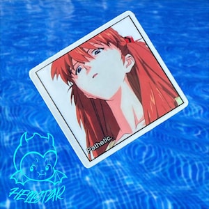 Puede incluir: Una pegatina cuadrada blanca con un personaje de anime de pelo rojo y la palabra "Pathetic". La pegatina está sobre un fondo de agua azul, con un logotipo de diablo azul neón y la palabra "HELLSTAR" debajo.