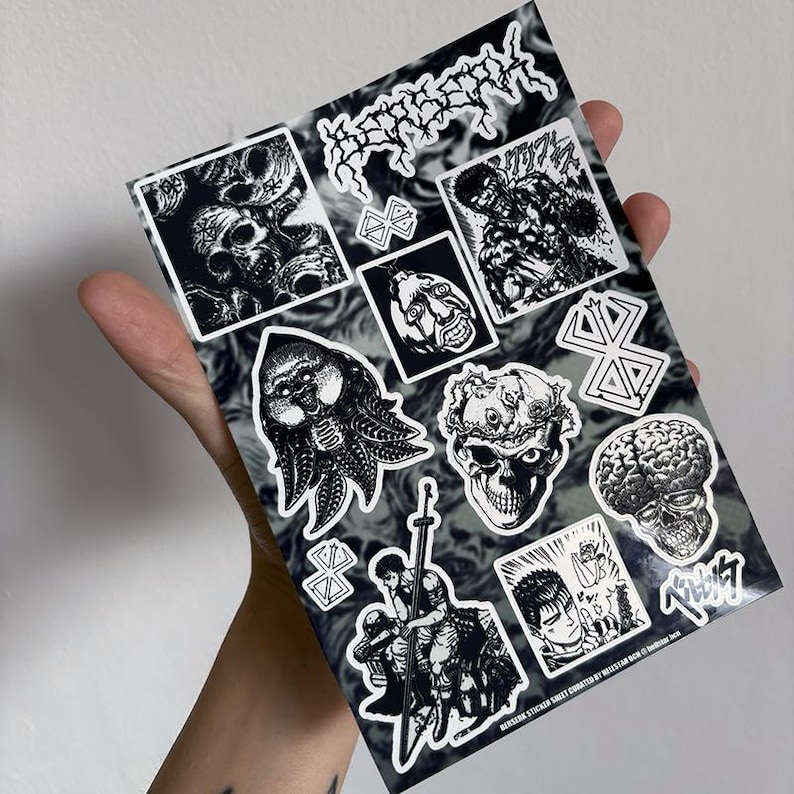 May include: A sheet of black and white stickers featuring various illustrations from the manga series Berserk. The stickers include characters, creatures, and symbols from the series. The sheet is printed with a black and white marbled background.