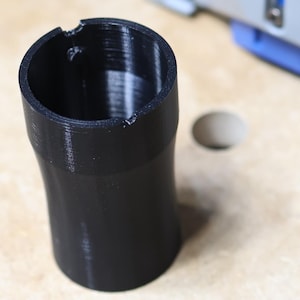 May include: A black plastic dust collection adapter for a Kreg circular saw. The adapter is designed to connect to a dust collection system.