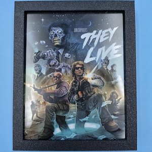 May include: Framed movie poster for "They Live" with a black textured frame. The poster features a zombie-like figure and action scenes. The title "THEY LIVE" is prominently displayed in white, with the director's name at the top.