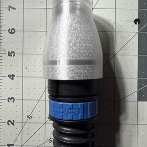 May include: A white plastic dust cover with a black and blue threaded connector. The connector has the text "Dust Right" printed on it.