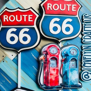 May include: A decorative Route 66 sign with a red and blue color scheme. The sign features the words "ROUTE" and the number "66". The image also includes red and blue gas pumps.