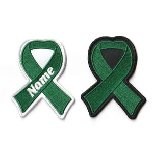 May include: Two green ribbon patches, one with a white background and the word "Name" embroidered on it, and the other with a black background. Both patches are embroidered with a green ribbon.