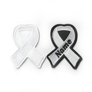 May include: Two white ribbon patches, one with the word "Nome" embroidered in black. The patches are iron-on and can be used to personalize clothing or bags.