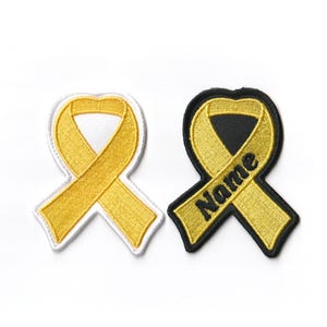 May include: Two yellow ribbon patches, one with a white background and one with a black background. The black ribbon patch has the word "Name" embroidered on it.
