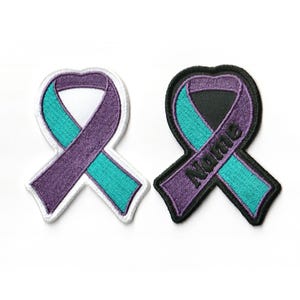 May include: Two embroidered ribbon patches, one white and one black. The ribbon is teal and purple. The black patch has the word "Name" embroidered on it.