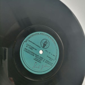 Puede incluir: Una etiqueta de disco de vinilo de color azul verdoso con el texto "ГОСТ 5289-56. Д-7982" y "БЕСПРИМЕРНЫЙ РЕЙС К ЗВЕЗДАМ СОВЕТСКИЙ ЧЕЛОВЕК В КОСМОСЕ" en escritura cirílica. La etiqueta también incluye el texto "33 1/3 об. в мин." y "Первая гр.-2 0-17".