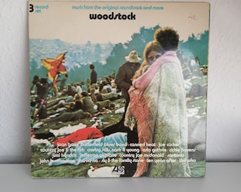 May include: A 3-record set vinyl record album cover featuring a photo of a crowd of people at the Woodstock music festival. The album cover is titled "Woodstock" and lists the artists featured on the album: Joan Baez, Butterfield Blues Band, Canned Heat, Joe Cocker, Country Joe & the Fish, Crosby, Stills, Nash & Young, Arlo Guthrie, Richie Havens, Jimi Hendrix, Jefferson Airplane, Country Joe McDonald, Santana, John Sebastian, Wha-na-na, Sly & the Family Stone, Ten Years After, and The Who.