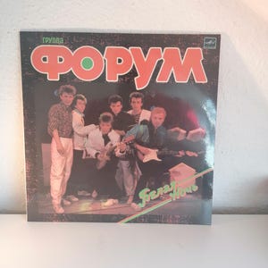 Peut inclure: Une pochette d'album de disque vinyle vintage mettant en scène un groupe appelé "ФОРУМ" avec le texte "Белая ночь" en lettres vertes et rouges. Les membres du groupe sont habillés à la mode des années 1980 et tiennent des instruments de musique.