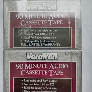 Könnte beinhalten: Zwei transparente Plastikhüllen mit 90-minütigen Audio-Kassetten. Die Hüllen sind mit "VeraTron" und "90 MINUTE AUDIO CASSETTE TAPE" beschriftet. Der Text auf den Hüllen lautet außerdem "Geringe Rauschanfälligkeit und hohe Ausgangsleistung", "Normales Vormagnetisieren 120 μs EQ", "Ideal für häufiges Wiederholen", "Hochwertige Leistung" und "VOLLSTÄNDIGE LEBENSLANGE GARANTIE".