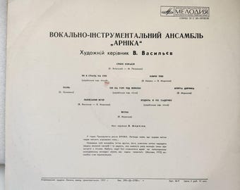 May include: A black and white record album cover with the title "Арніка" in Cyrillic script. The album features a vocal-instrumental ensemble and is directed by V. Vasilyev. The back cover lists the songs on the album, including "Срібні Кораблі", "В Спала На Сні", "Коло Тієї", "Осінь", "Он На Горі Під Вербою", "Вперта Діачина", "Лявісний Вечір", "Коли Я В По Садочку", and "Весна".