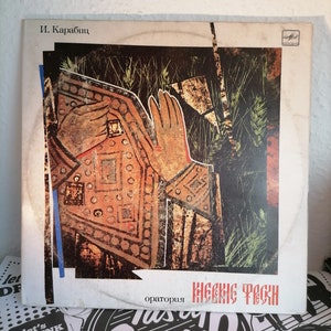 May include: A white vinyl record with a painting of a hand in a field of wheat. The record is titled "Иессеея песня" and is by "И. Карабиц".