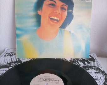 Puede incluir: Un disco de vinilo negro con una etiqueta blanca que muestra una foto de Mireille Mathieu, una cantante francesa, y el texto "Mireille Mathieu - Amor y Vida" en cirílico. La etiqueta del disco también incluye el texto "Melodiya" y "C80-0813".
