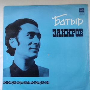 以下が含まれることがあります： 水色の背景に、男性の白黒ポートレートと白と黒のテキストが特徴の、ヴィンテージビニールレコードアルバムのカバー。「Батыр Закиров」という名前のテキストが含まれています。