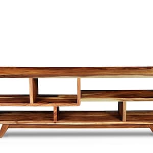 May include: A wooden entertainment unit with a natural wood finish and a modern design. It features multiple shelves and a unique open-frame construction.
