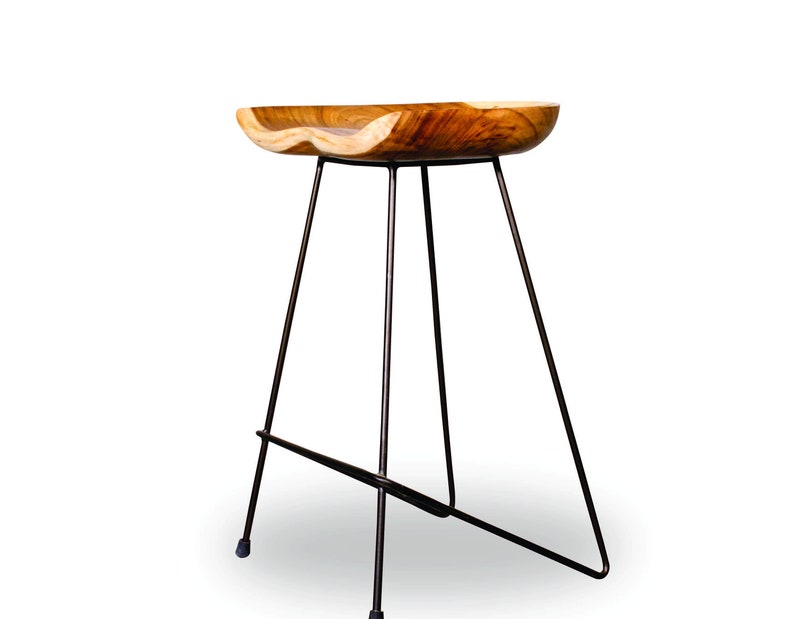 Peut inclure: Tabouret de bar en bois avec une assise incurv&eacute;e naturelle et des pieds en m&eacute;tal fonc&eacute;. L'assise est en bois brun clair avec un motif de grain unique. Les pieds sont fins et inclin&eacute;s, offrant un design moderne et minimaliste.