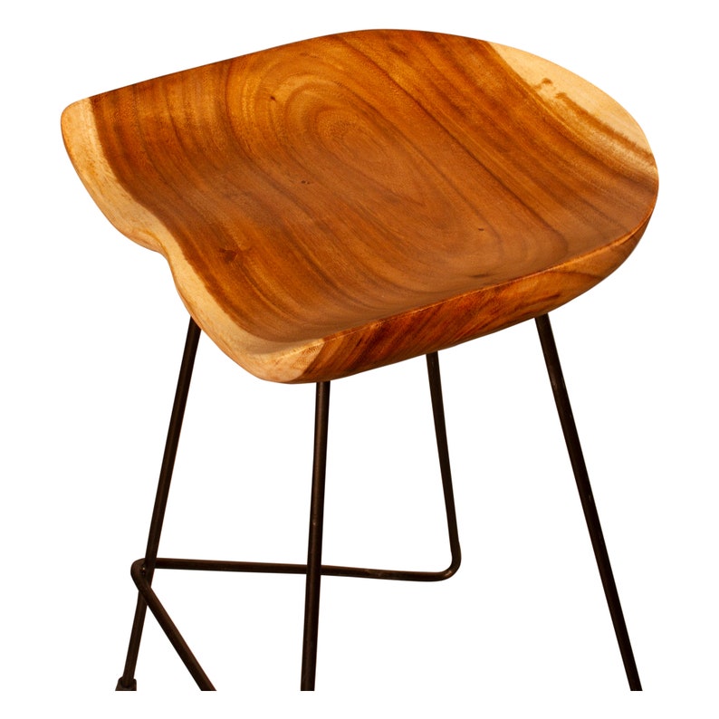 Peut inclure: Tabouret en bois avec une forme naturelle et organique. L'assise est faite d'une seule pi&egrave;ce de bois, mettant en valeur le grain et les variations de couleur. Il poss&egrave;de trois pieds en m&eacute;tal fonc&eacute;, offrant une base solide. Le design du tabouret est moderne et minimaliste.