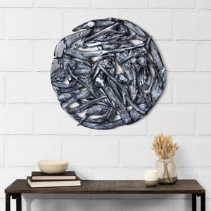May include: A circular wall decor made of silver-painted driftwood branches arranged in a random pattern. The decor is mounted on a white brick wall.