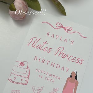 May include: A pink and white birthday card with the text "Kayla's Pilates Princess Birthday September 14 2025". The card features illustrations of a gym bag, shoes, a martini, and a woman in a pink jumpsuit.