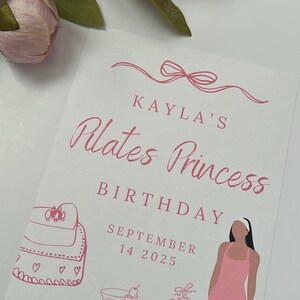 May include: A white card with pink text and illustrations. The text reads "Kayla's Pilates Princess Birthday September 14 2025." Illustrations include a purse, ballet slippers, a cocktail, hearts, dumbbells, and a woman in a pink jumpsuit.