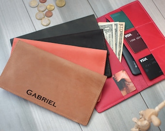 May include: A set of four leather wallets in different colors, including red, orange, brown, and black. The wallets are stacked on top of each other and have a personalized inscription that reads "GABRIEL".