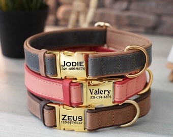 May include: Three leather dog collars stacked on top of each other. The top collar is gray with a tan trim, the middle collar is pink with a red trim, and the bottom collar is tan with a brown trim. Each collar has a gold buckle with a personalized name and phone number. The top collar says "JODIE 321-456-9874", the middle collar says "Valery 321-654-1895", and the bottom collar says "ZEUS 123-987-6547".