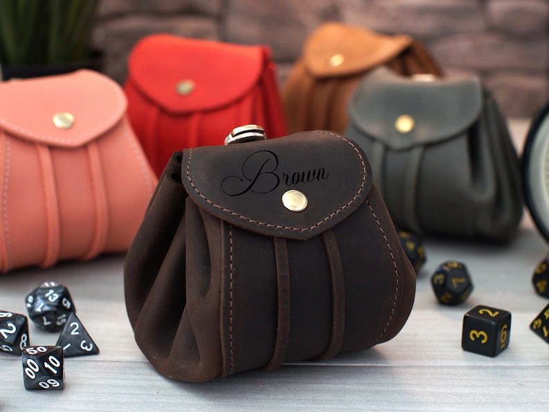 Pode incluir: Saco de dados de couro marrom com fecho de aba e design costurado. A bolsa &eacute; personalizada com a palavra "Brown" em it&aacute;lico.