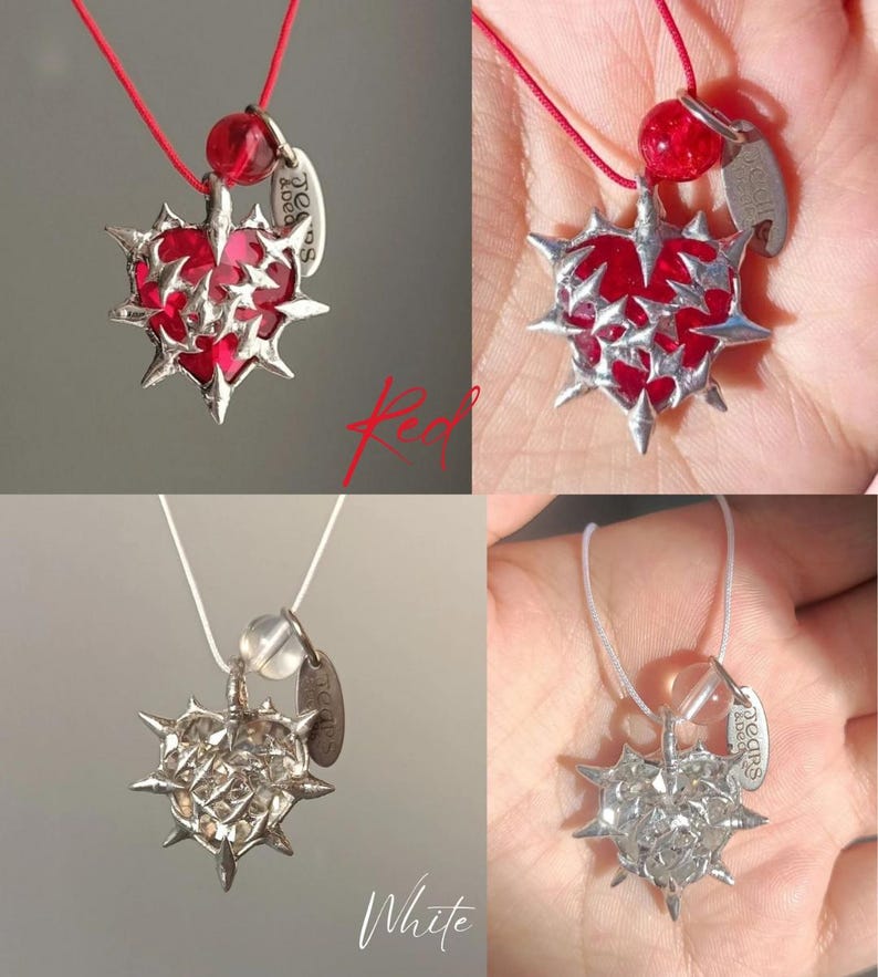 May include: A silver necklace with a red heart pendant. The heart is covered in spikes and has a silver tag that says "Saddles & Love".