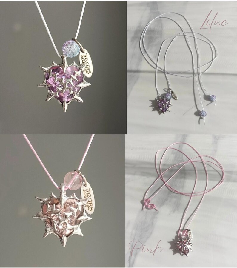 May include: Two necklaces with a silver heart pendant with spikes and a pink or purple crystal heart. The pendant has a small tag that says "Tears & Love". The necklaces are on a white or pink cord.