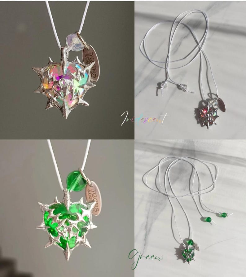 May include: Two necklaces with a heart-shaped pendant with a thorny design. The pendant on the left is iridescent and the pendant on the right is green. Both pendants have a small tag that says "Yours Forever".