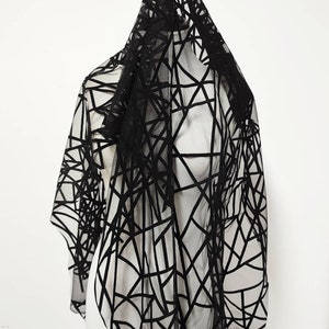 May include: Black sheer fabric with a geometric pattern of black velvet lines. The fabric is draped over a dress form.