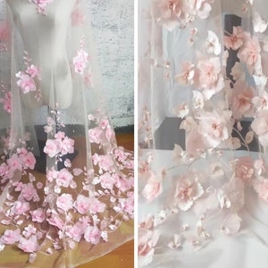 Puede incluir: Tela de encaje floral 3D rosa con delicadas flores y hojas sobre un fondo de malla transparente.