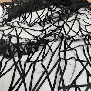 May include: Black sheer fabric with a geometric pattern of thick black lines.