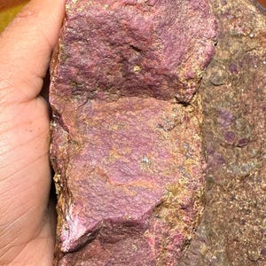 May include: A large, rough, pink and gold colored rock. The rock has a rough, uneven surface and is a natural, unpolished stone.