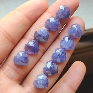 May include: A collection of ten faceted heart-shaped amethyst gemstones. The amethyst is a light purple colour.