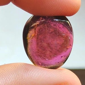 Könnte beinhalten: Ein glatter, ovaler, rosa-grüner Edelstein mit durchscheinender Optik.