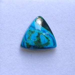 May include: A triangular gemstone with a polished surface. The stone features a vibrant blend of turquoise and deep green hues, with swirling patterns and a glossy finish. The gemstone is set against a white background.
