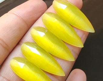 May include: Five yellow teardrop-shaped cabochon stones with a chatoyant effect.
