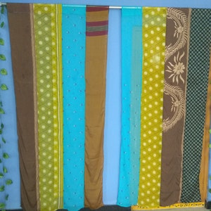 May include: A wall decorated with a series of colorful fabric panels, each with a different pattern. The panels are hung on a rod and are arranged in a vertical line. The panels are a mix of brown, green, blue, and yellow.