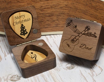 May include: Two wooden boxes with engraved designs. One box has a guitar with musical notes and the word "Dad" engraved on it. The other box has a Christmas tree and the words "Merry Christmas" engraved on it.