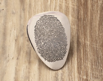 May include: Silver guitar pick with a fingerprint design.
