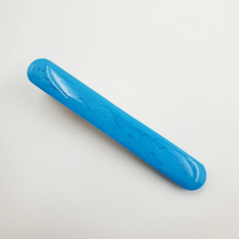 Op de afbeelding: Een lange, dunne, blauwe haarspeld met een marmerpatroon.