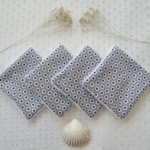 May include: Five black and white patterned fabric squares with a white border. The squares are stacked on top of each other and have a hexagonal pattern.