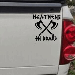 May include: Black and white sticker with the text "HEATHENS ON BOARD" and a graphic of two crossed axes.